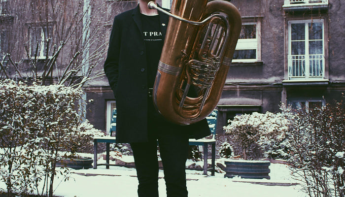 Wessex Tubas' Principal Performing Artist Will Druiett stands in front of a snowy suburban area with the BBb 6/4 Rotary Tuba ‘Kaiser’