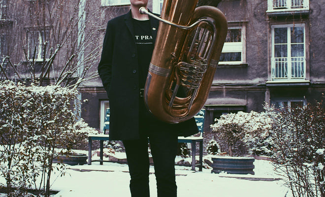 Wessex Tubas' Principal Performing Artist Will Druiett stands in front of a snowy suburban area with the BBb 6/4 Rotary Tuba ‘Kaiser’